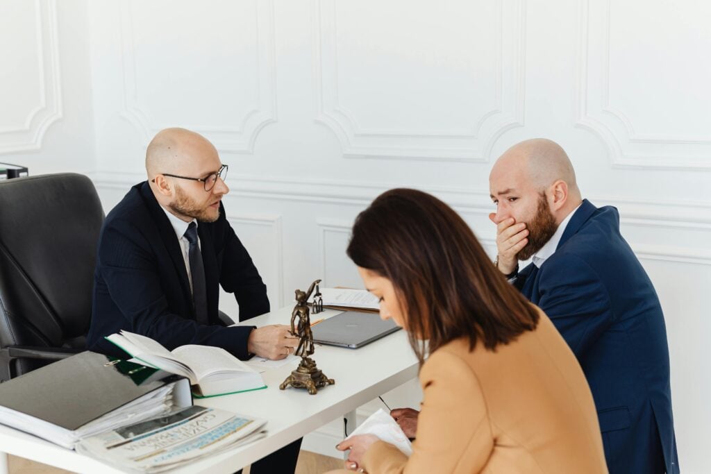 A serious legal consultation in a professional office environment involving three adults.